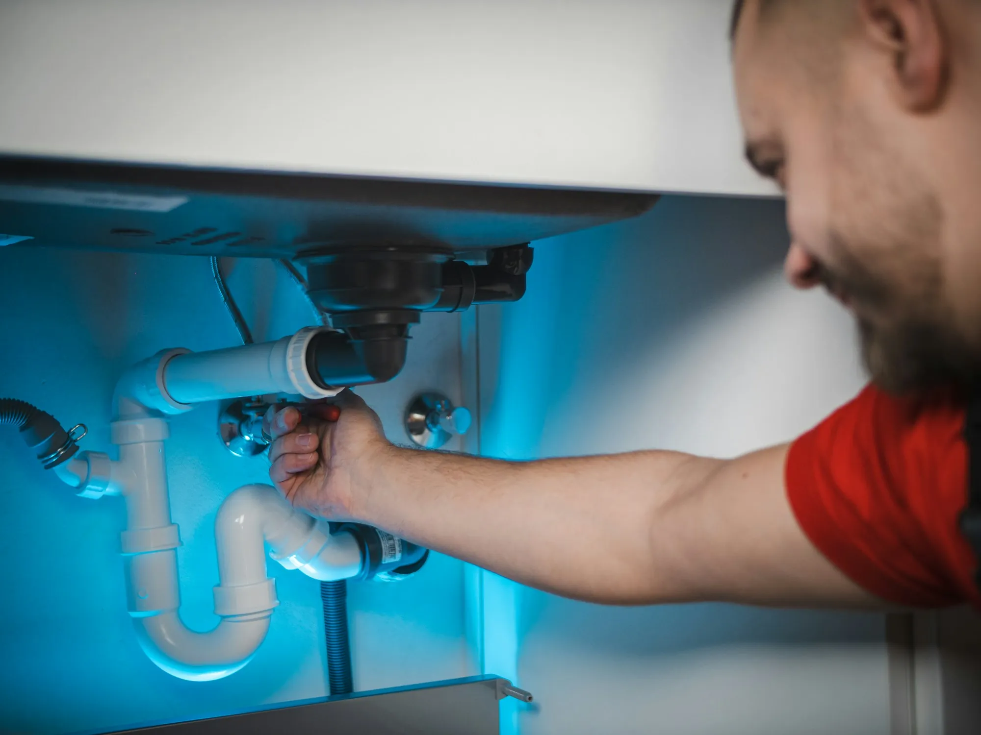 Technician working on plumbing under a kitchen sink
