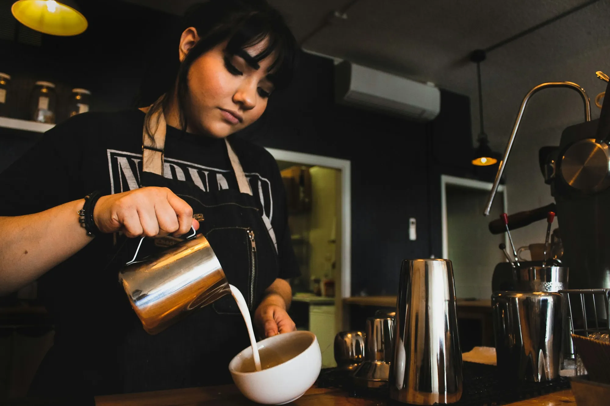 Barista pouring steamed milk in a cafe